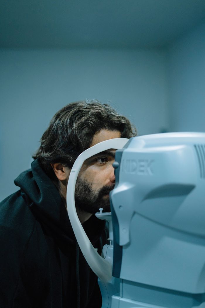 A man undergoing an eye examination using a medical device in a clinic setting.
